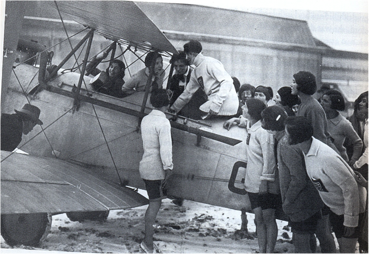 Mary demonstrating the controls of her aeroplane to a group of school girls